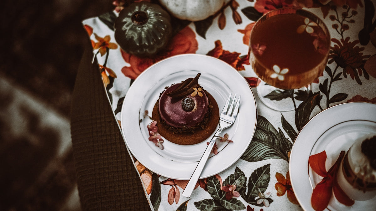 Chocolate cake with fork on floral tablecloth with pumpkins