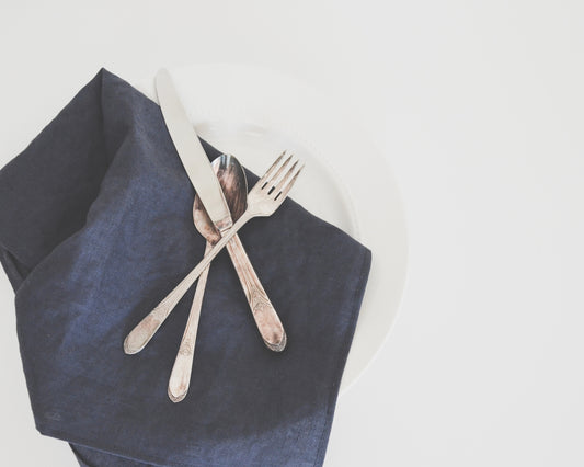 gray fork, spoon, and butter knife on plate with black table napkin