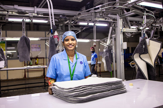 A factory worker smiles in a manufacturing plant.