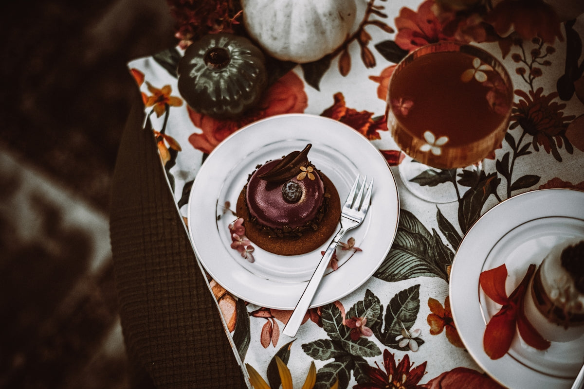Chocolate cake with fork on floral tablecloth with pumpkins